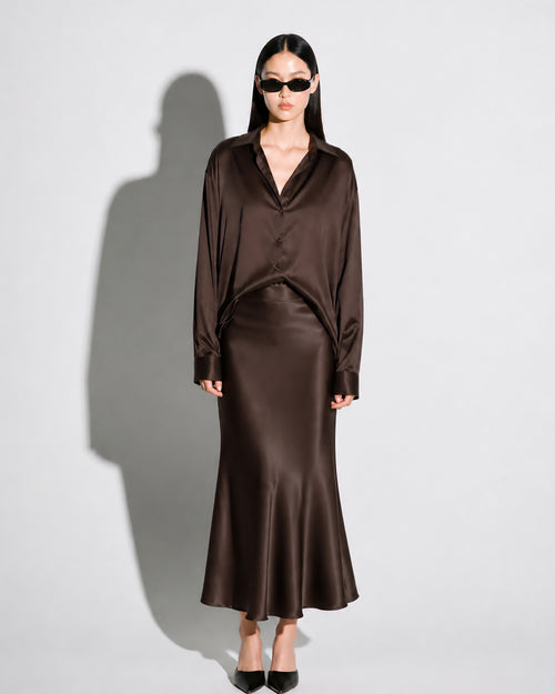 Woman wearing a brown satin outfit on a plain background