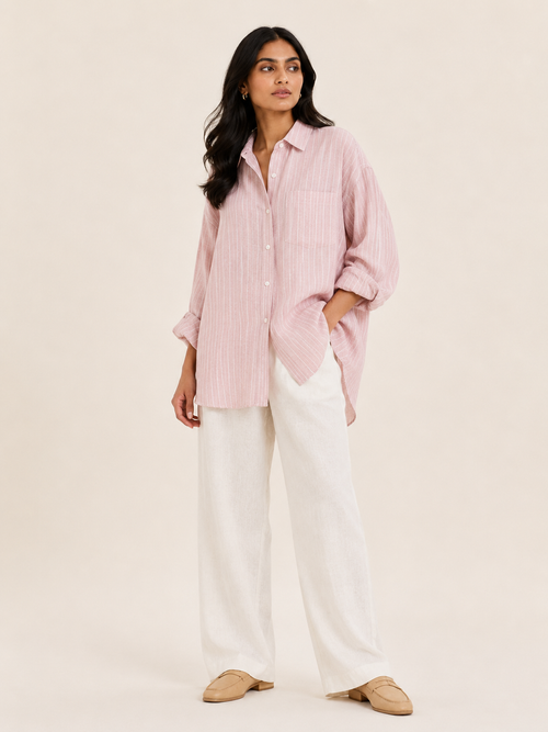 Woman wearing a pink striped shirt and white pants on a beige background
